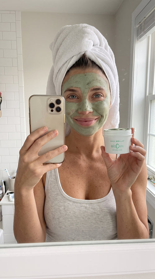 Mujer usando la mascarilla de arcilla verde frente al espejo